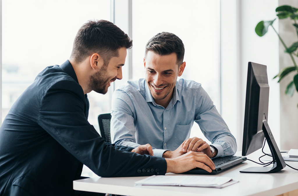 realistic_picture_of_two_men_sitting_in_an_office_one_shows_the_other_something_on_a_computer_they__bifbexuqtkneplbrj8ko_5